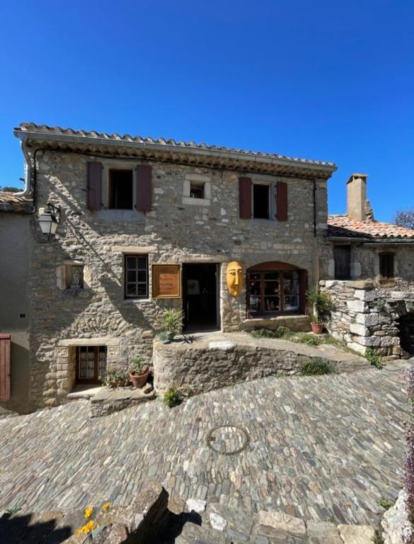 une grande maison en pierre avec une allée en pierre dans l'établissement appartement chez l'artiste, à Minerve