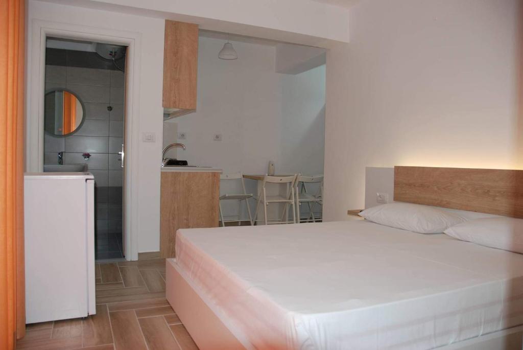 1 dormitorio con 1 cama blanca grande y cocina en The Hill Apartment, en Sarandë