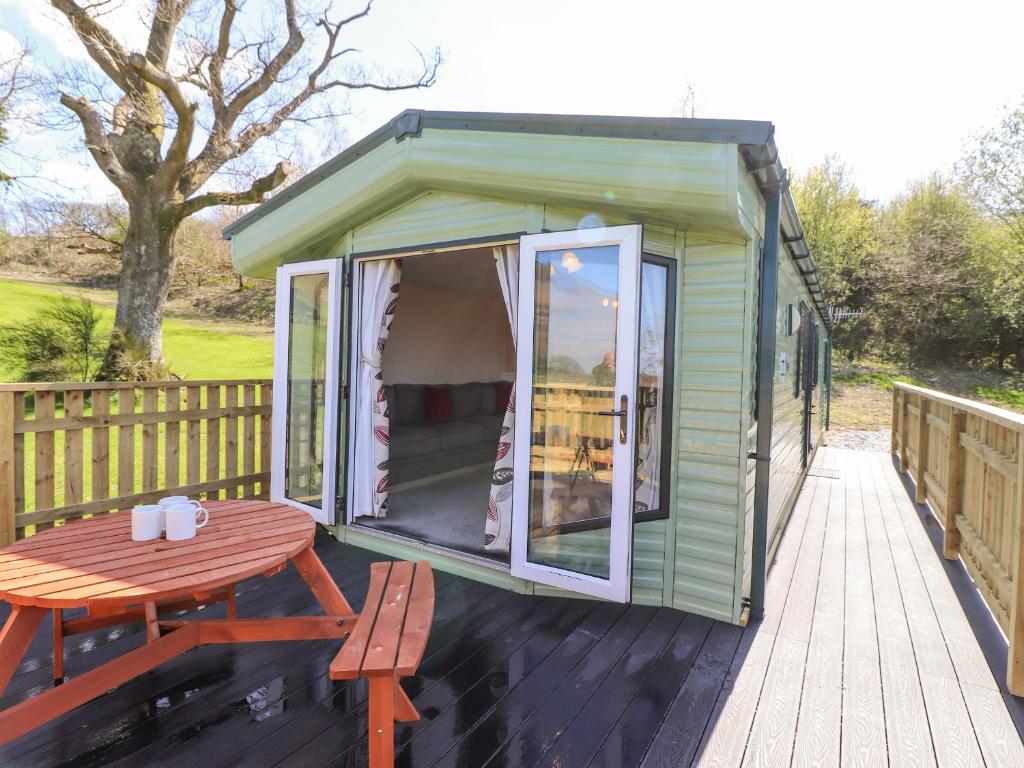 a green tiny house with a table and a picnic table at Swinside in Cockermouth