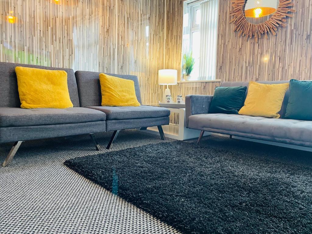 uma sala de estar com 2 sofás azuis e almofadas amarelas em Holywell Apartment - Luxury One Bedroom Apartment em Holywell