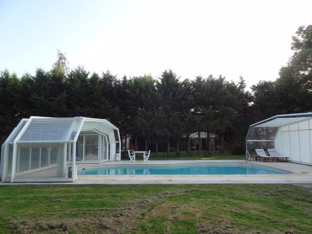uma estufa em torno de uma piscina ao lado de uma casa em Villa de campagne avec piscine em Beaulieu-sur-Loire