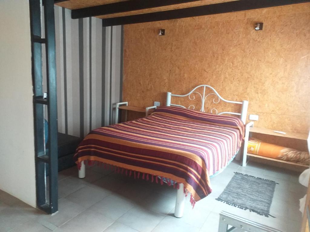 1 dormitorio con 1 cama con manta a rayas en Jeluma1 en Vaqueros