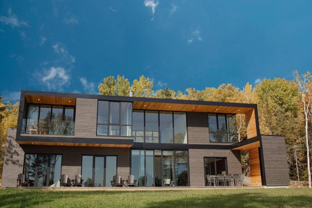 a large house with glass windows at Le Ruisseau: luxurious villa in Charlevoix. in La Malbaie