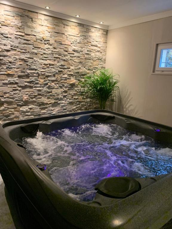 a hot tub in a room with a stone wall at Gîte Bien-être in Yquebeuf