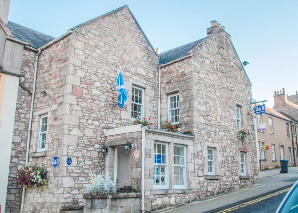 a stone building with a flag on a street at Meadhon Guest House in Jedburgh