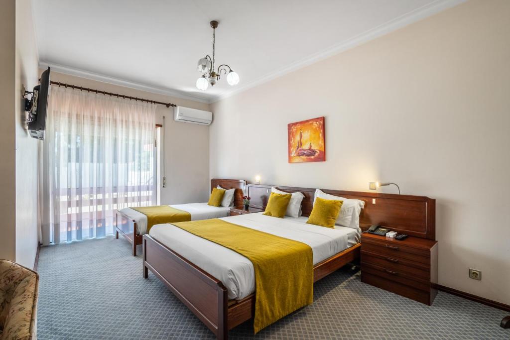 a hotel room with two beds and a window at Hotel Colmeia in Monte Real
