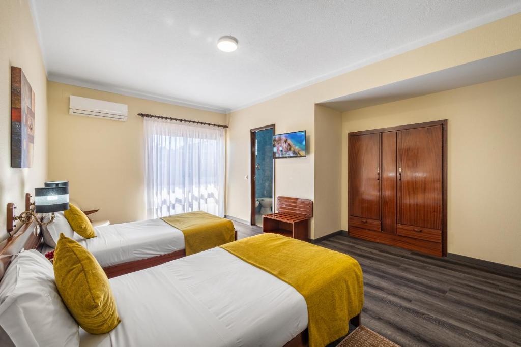 a hotel room with two beds and a cabinet at Hotel Colmeia in Monte Real