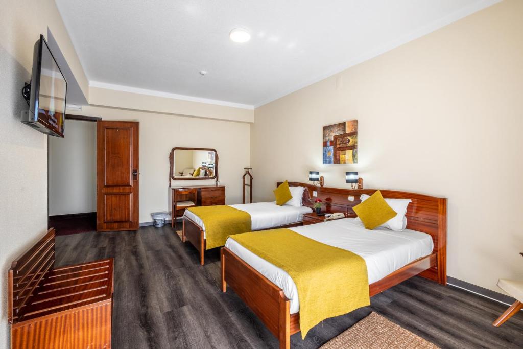 a hotel room with two beds and a mirror at Hotel Colmeia in Monte Real