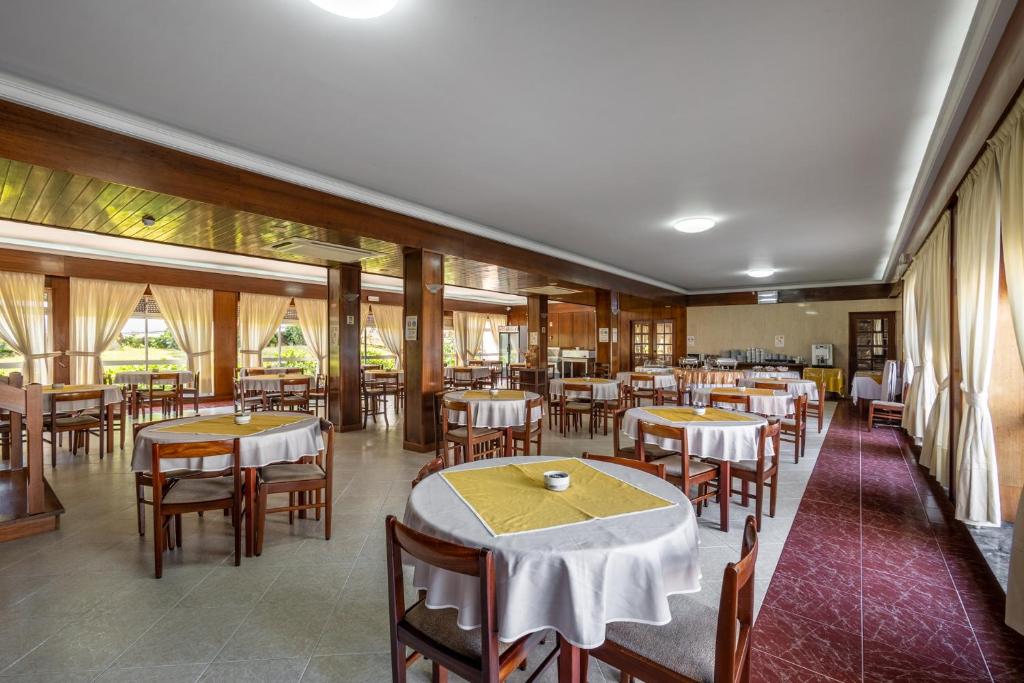 a dining room with tables and chairs and windows at Hotel Colmeia in Monte Real