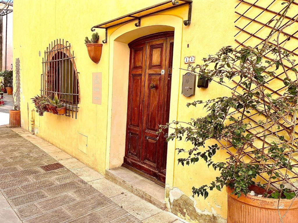 a yellow building with a wooden door on a street at La cicala in Rosignano Marittimo