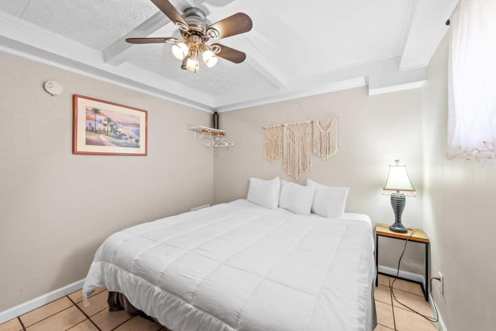 a bedroom with a white bed and a ceiling fan at Great Location 1BR Pool Parking Pets Allowed 5 in Myrtle Beach
