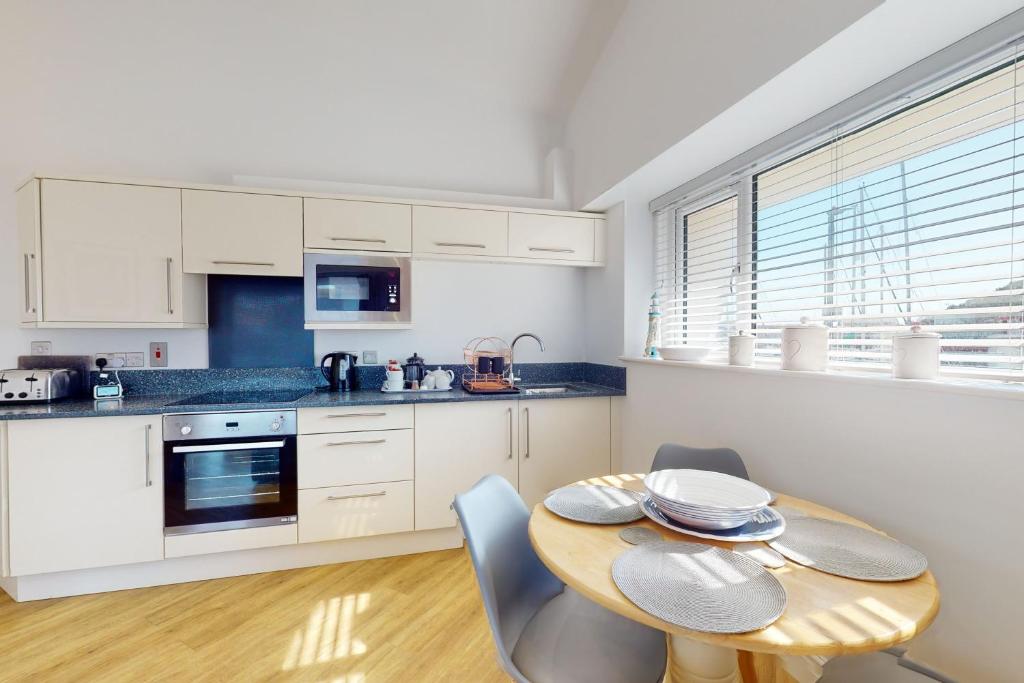 a kitchen with white cabinets and a wooden table with chairs at Crabbers' Wharf in Portland