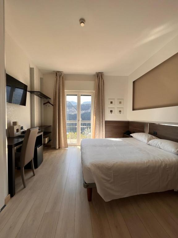 sypialnia z łóżkiem, biurkiem i oknem w obiekcie Hotel Isola Verde w orbole