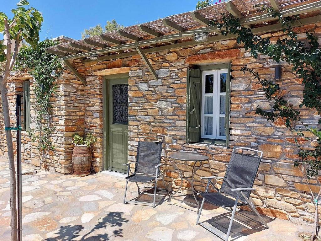 a patio with two chairs and a table in front of a stone building at K-Homes Superior double in Tinos Town