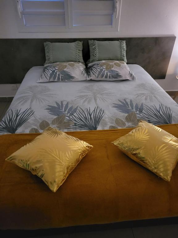 a bed with two yellow pillows on top of it at Les gîtes de Macca in Saint-François