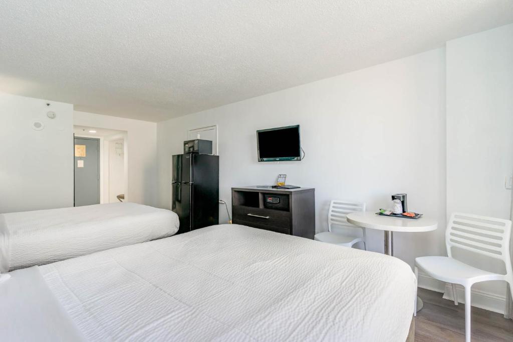 a bedroom with two beds and a table and a tv at Sun N Sand Resort in Myrtle Beach