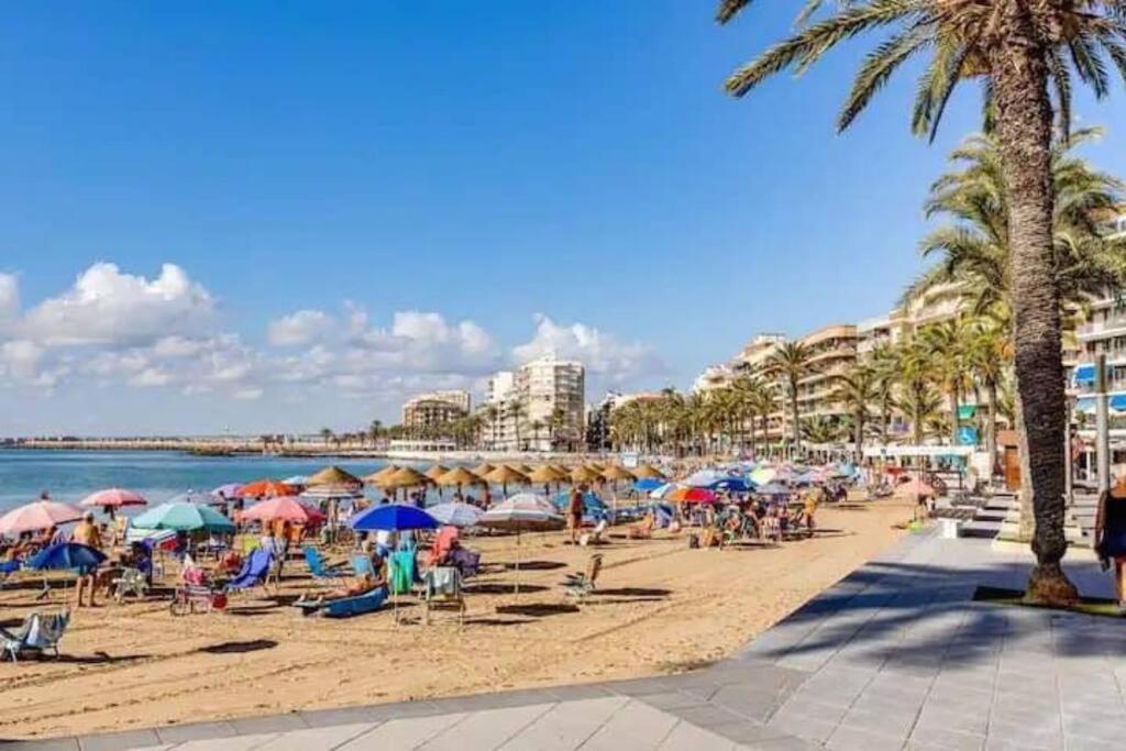 - une plage avec des parasols et des personnes assises sur le sable dans l'établissement 2Bdr Apartment, à Torrevieja