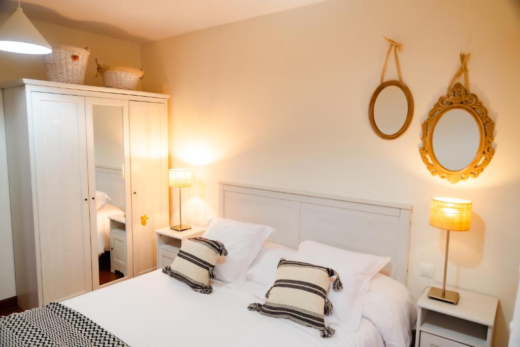 1 dormitorio con 1 cama blanca y 2 almohadas blancas y negras en Apartamentos Costa Norte, en San Vicente de la Barquera