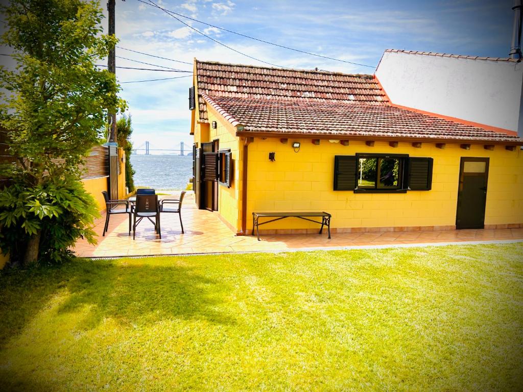 a yellow house with a table and chairs on a deck at CASA O PIÑEIRO in Redondela