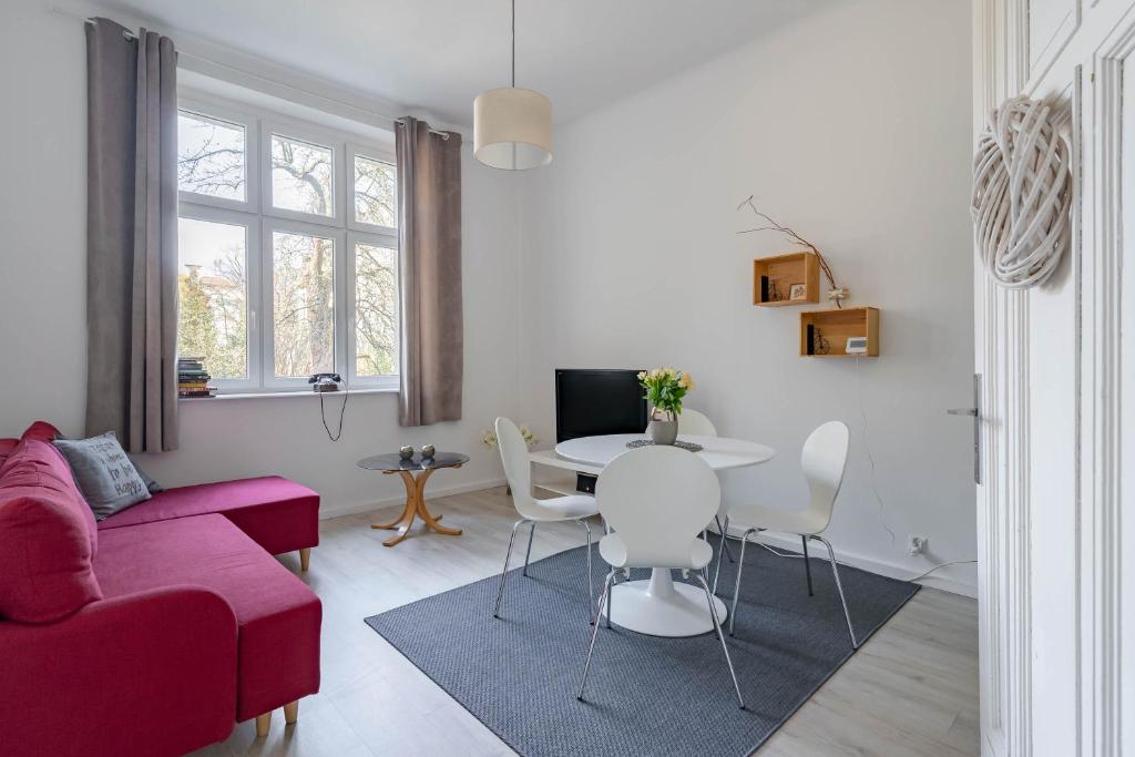 ソポトにあるKierunek Sopot Apartament DELUXE II Królowej Jadwigi 7のリビングルーム(赤いソファ、テーブル付)