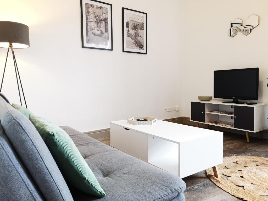 sala de estar con sofá y TV en Le petit cocon de la poste, en Gourdon-en-quercy