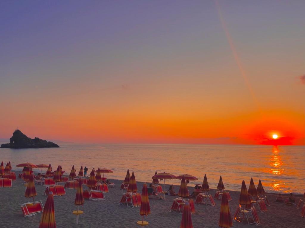 a beach with chairs and umbrellas at sunset at La Tonnara B&B in Palmi