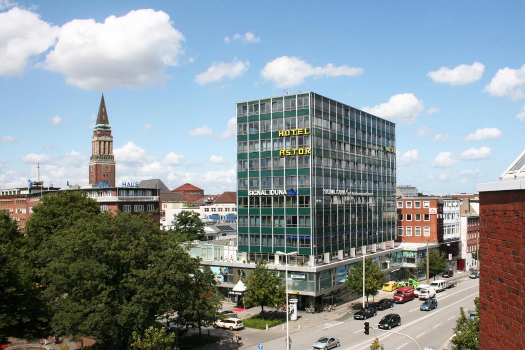 um edifício de vidro alto com um relógio sobre ele em uma cidade em Hotel Astor Kiel by Campanile em Kiel