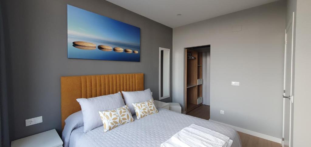 ein Schlafzimmer mit einem Bett und einem Wandgemälde in der Unterkunft Pisos uso turistico Torno-Cubelas-Caosa Buenavista in San Cibrao