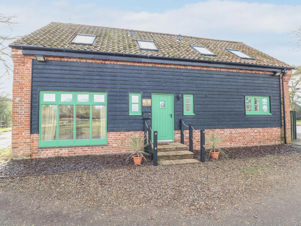 ein kleines Haus mit grüner Tür und Fenstern in der Unterkunft The Old Cartshed in Lowestoft