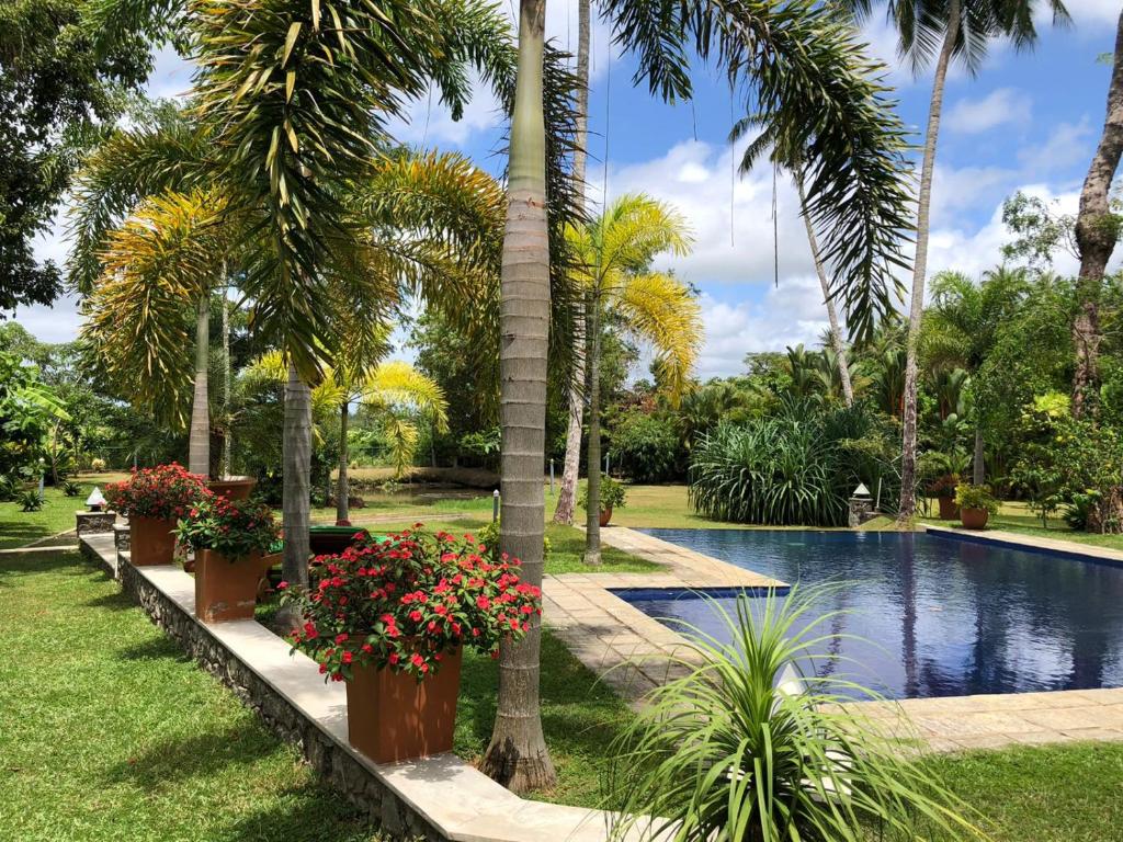 a swimming pool in a park with palm trees and flowers at Avalon Village Resort in Induruwa