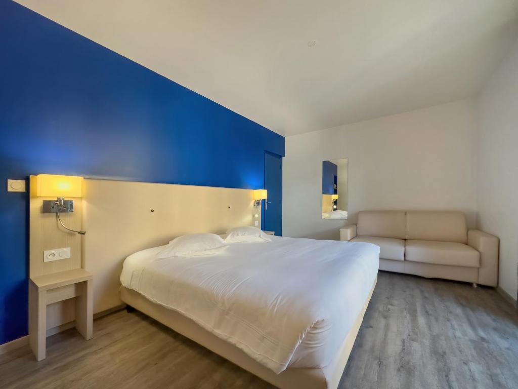 a bedroom with a white bed and a blue wall at Hotel De La Gare in Quimper