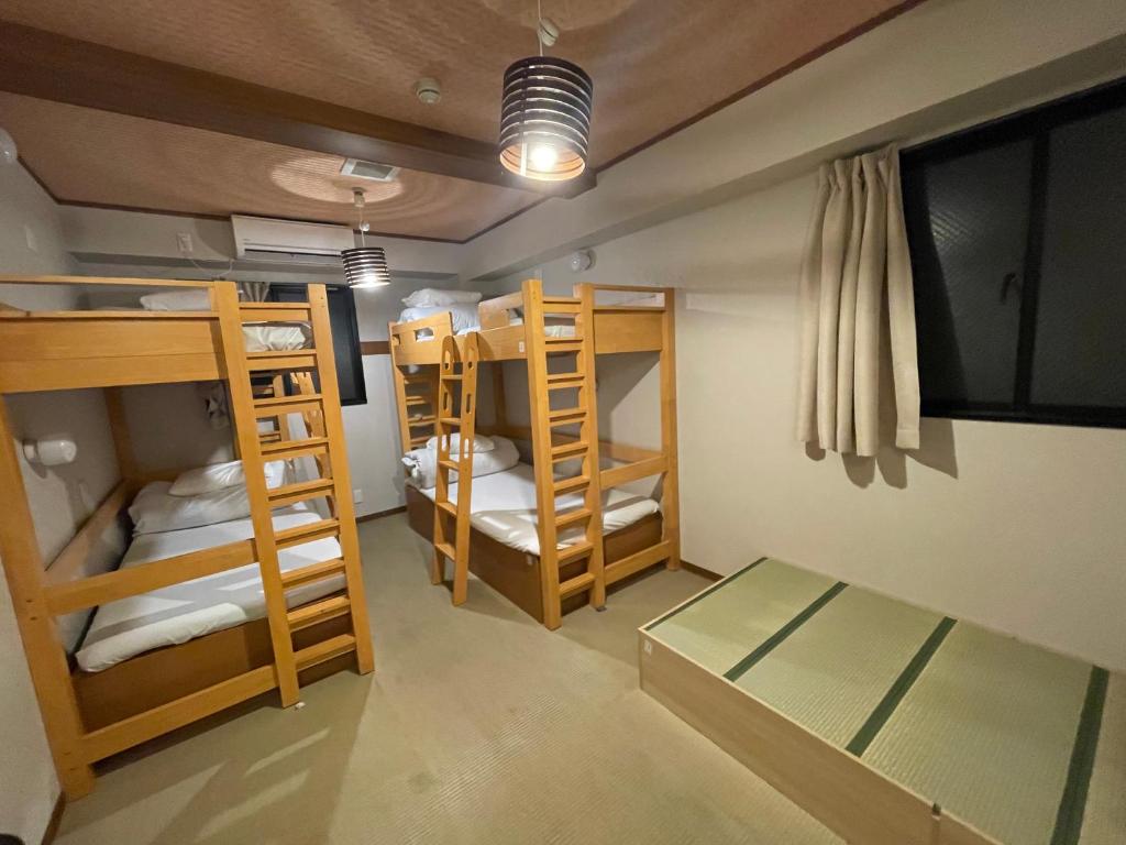 a room with three bunk beds and a table at TenTen Guesthouse in Asakusa in Tokyo