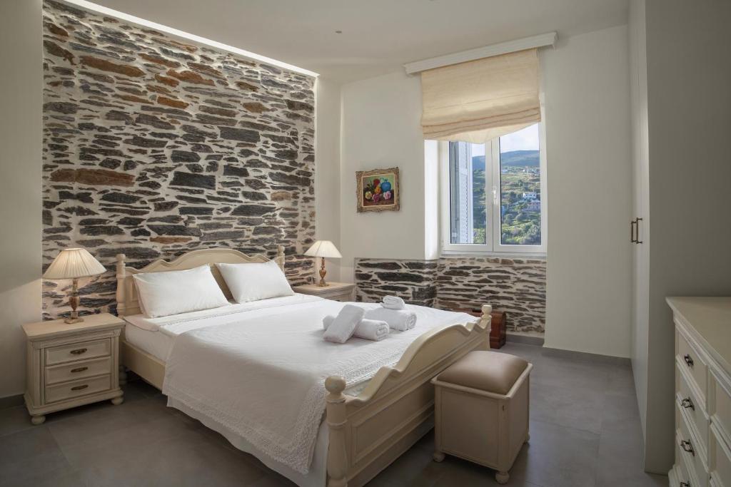 1 dormitorio con 1 cama grande y pared de piedra en Alpha House Gialia, en Ándros