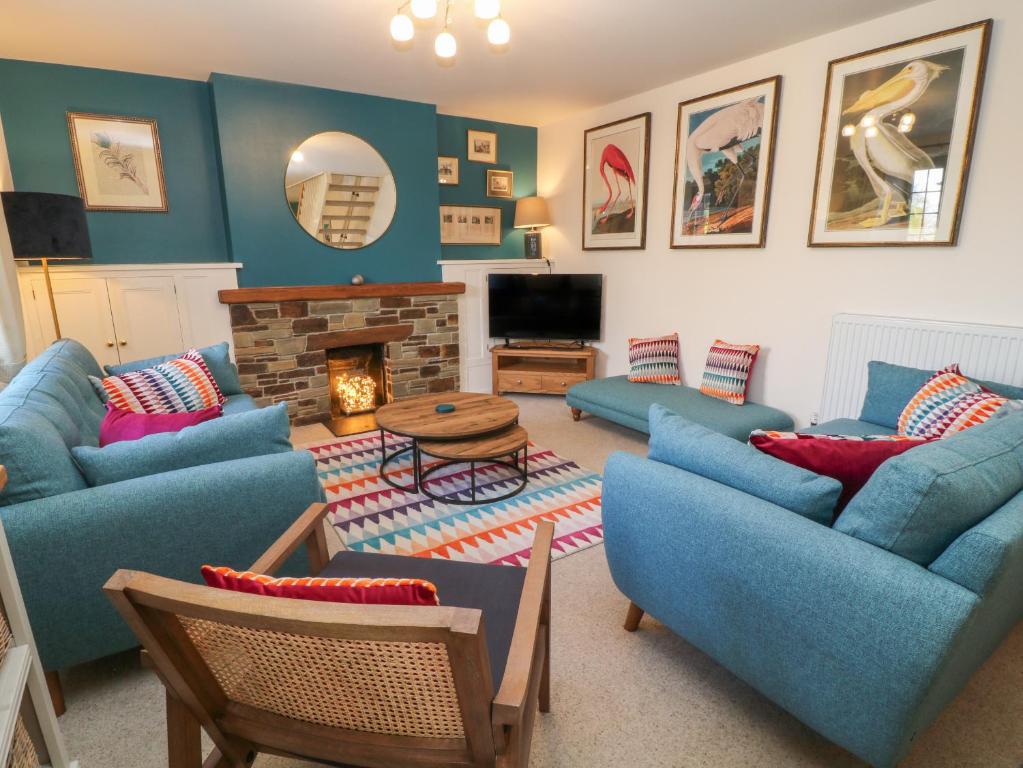 ein Wohnzimmer mit blauen Sofas und einem Kamin in der Unterkunft Church Hill Cottage in Tavistock