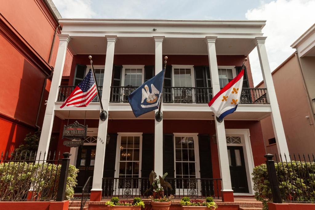 a red building with three flags in front of it at Le Richelieu in the French Quarter in New Orleans