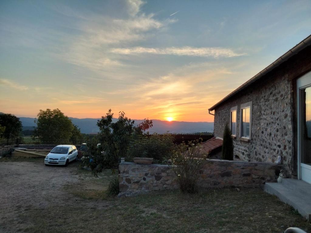 a car parked in front of a house with the sunset at Gîte du Bachat in Vorey