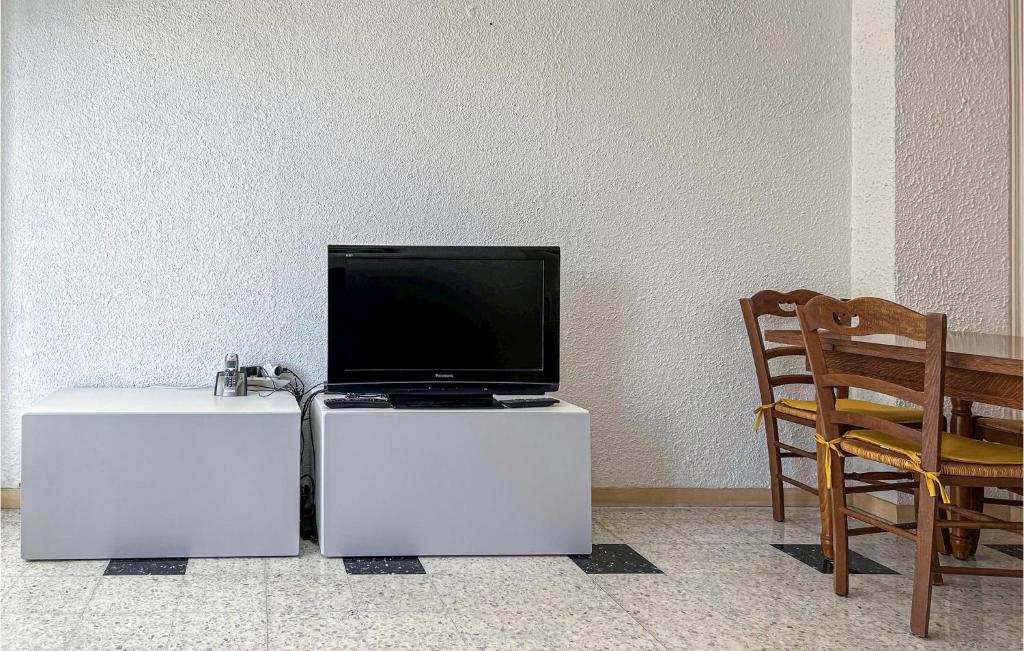 a tv sitting on top of a white stand next to a chair at 1 Bedroom Awesome Apartment In Le Cannet in Le Cannet