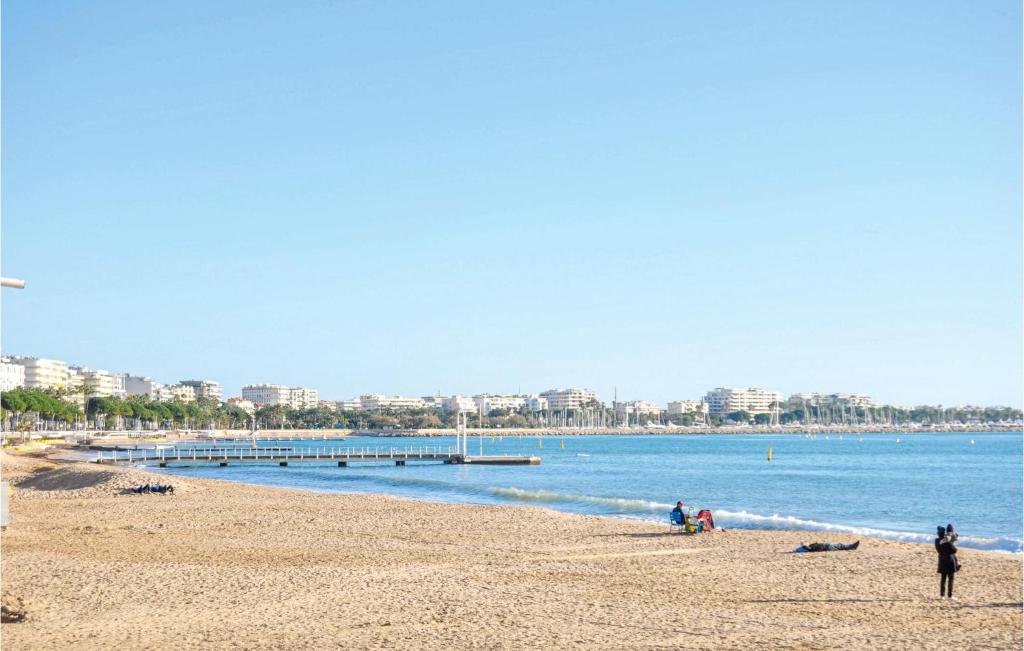 a beach with people sitting on the sand and the water at 1 Bedroom Awesome Apartment In Le Cannet in Le Cannet