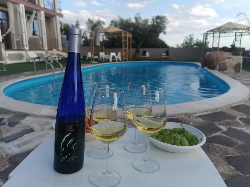 uma garrafa de vinho e copos numa mesa ao lado de uma piscina em Etnadia em Santa Maria di Licodia