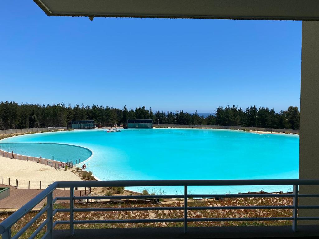 a large pool of blue water with trees in the background at Laguna mar in Las Cruces