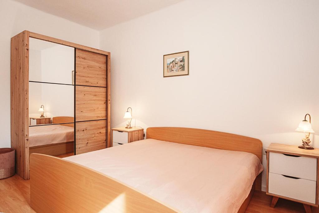 a small bedroom with a bed and a mirror at Apartments Tončica in Božava