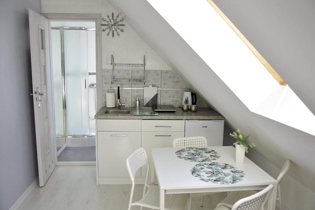 a white kitchen with a white table and chairs at Apartament Słoneczny in Mrągowo