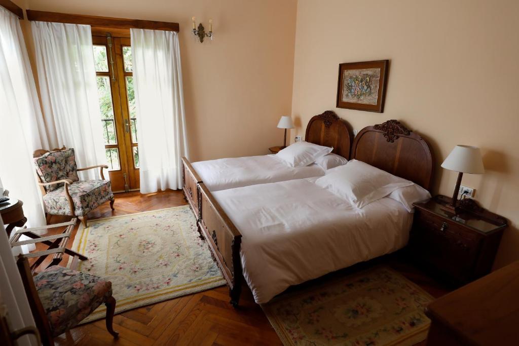 a bedroom with two beds and a chair and a window at Hotel Hontoria in Hontoria