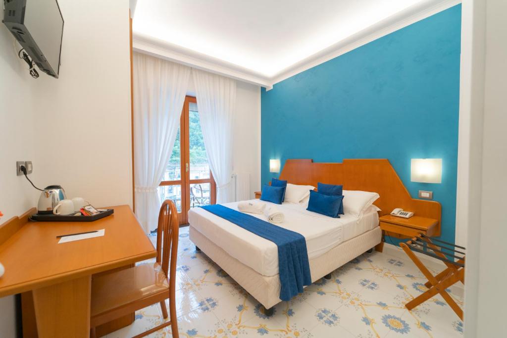 Schlafzimmer mit einem Bett, einem Tisch und einem Schreibtisch in der Unterkunft Hotel San Pietro in Maiori