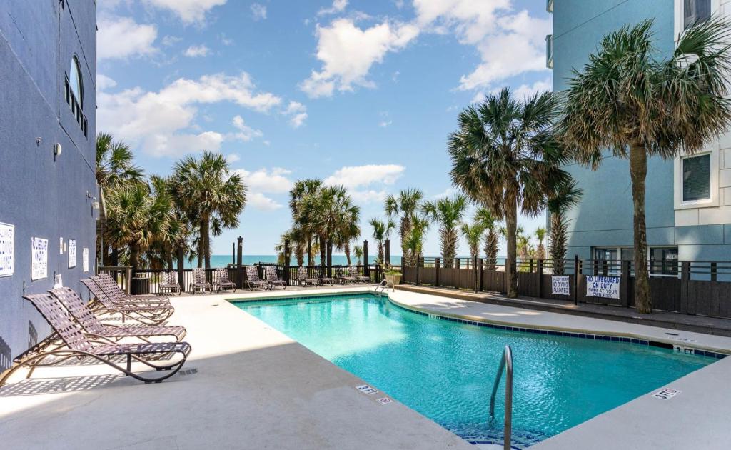 a pool with chairs and palm trees in a building at Sun N Sand Resort in Myrtle Beach