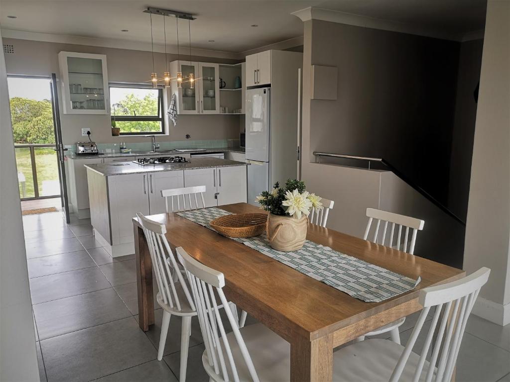 a kitchen with a wooden table and white chairs at Mount Castleton in Plettenberg Bay
