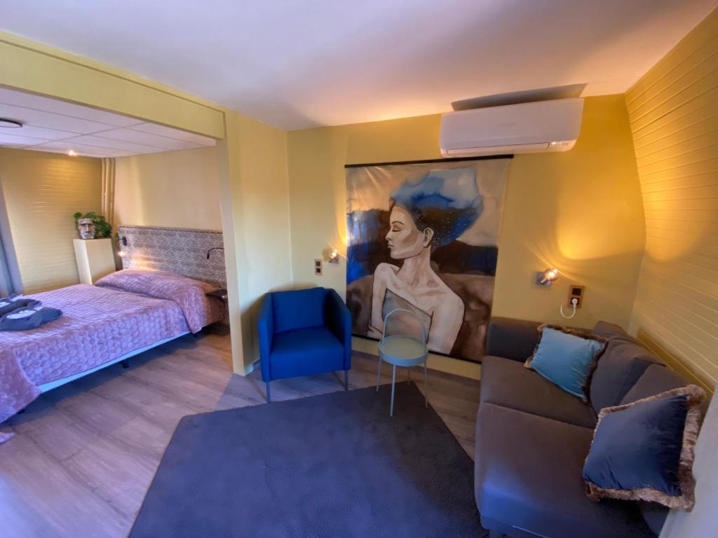 Habitación con sofá, cama y pintura en De Post B&B Restaurant en Klimmen