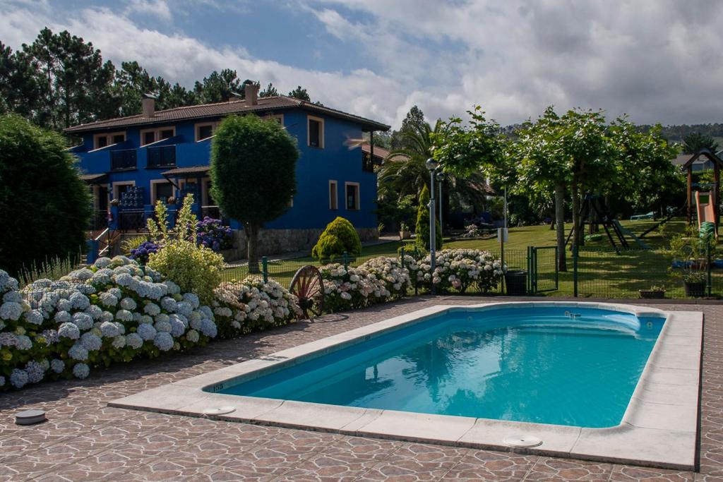 una piscina azul frente a una casa en Apartamentos y Habitaciones Casa Bego, en Valdredo