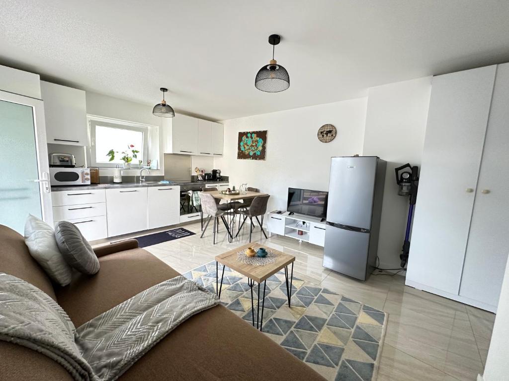 eine Küche und ein Wohnzimmer mit einem Sofa und einem Tisch in der Unterkunft Superbe appartement proche de stations de ski in Thonon-les-Bains