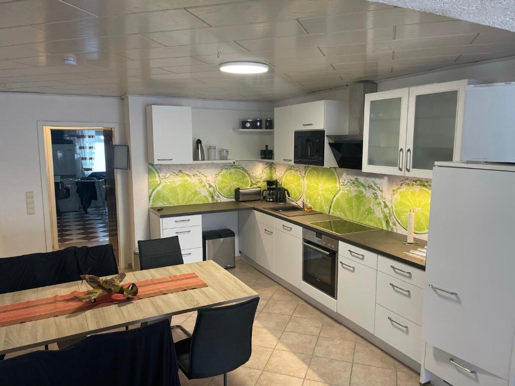 a large kitchen with white cabinets and a wooden table at Haus am See in Braunschweig